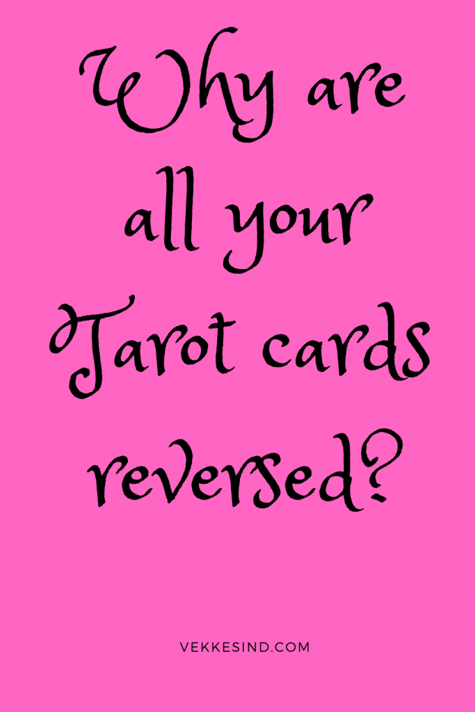 A tarot card lying reversed on a wooden table beside an open journal and a lit candle