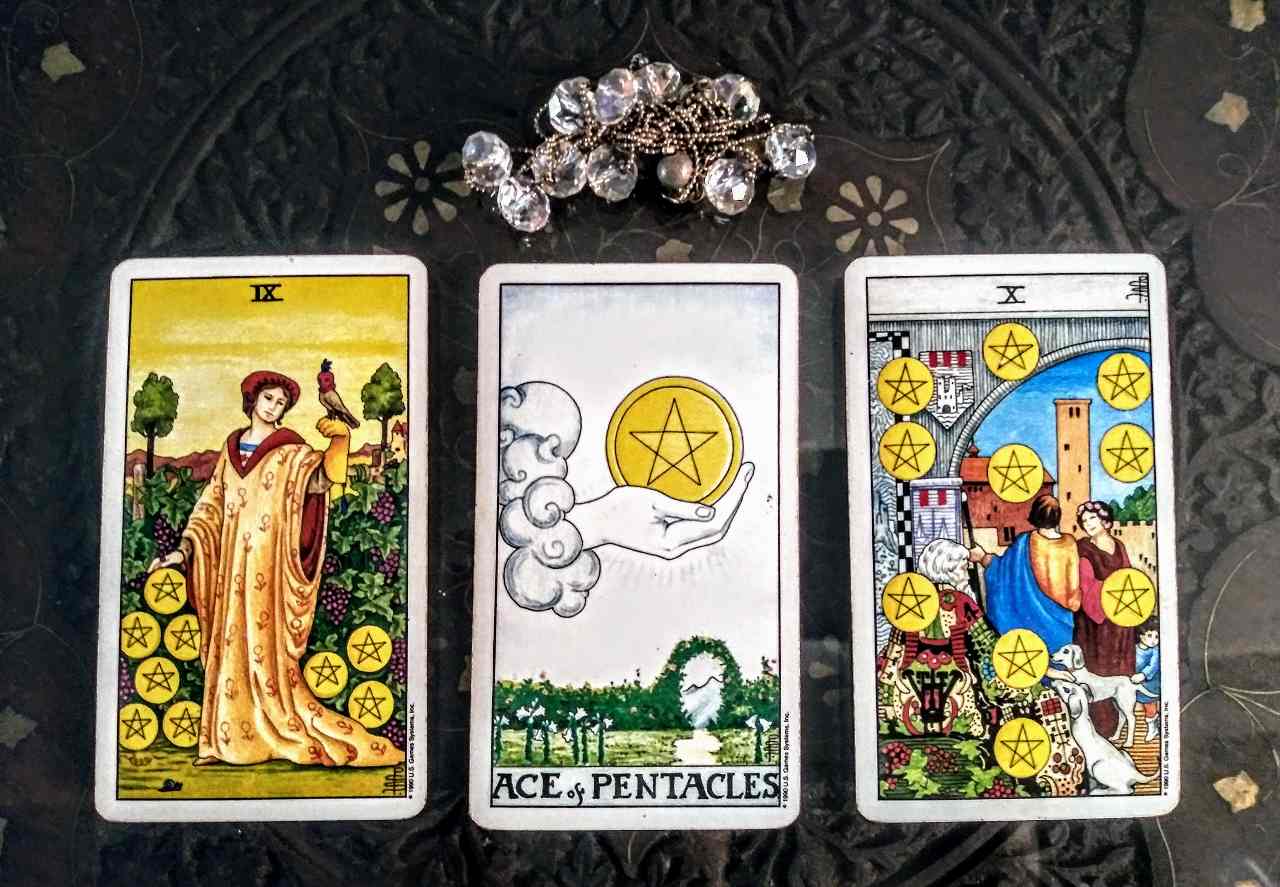 A three-card tarot spread representing a money manifestation layout with coins and green candle