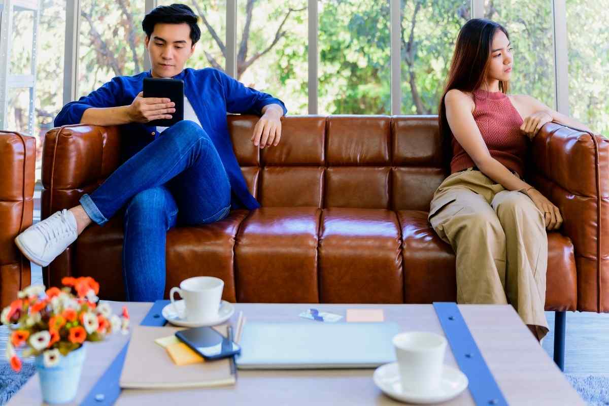 A couple sitting apart on a couch, no longer connected or communicating