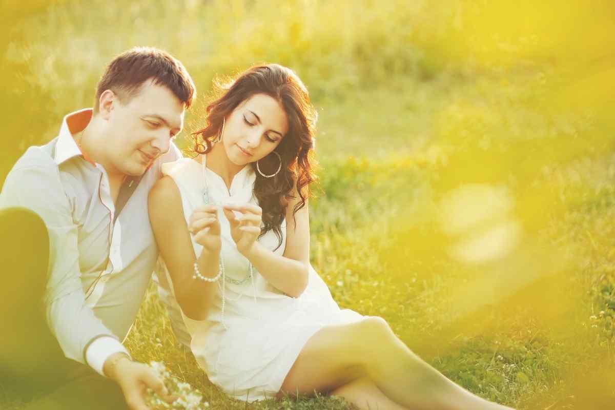 A man and woman sitting at a distance from each other, both turned slightly away, suggesting emotional withdrawal from the relationship