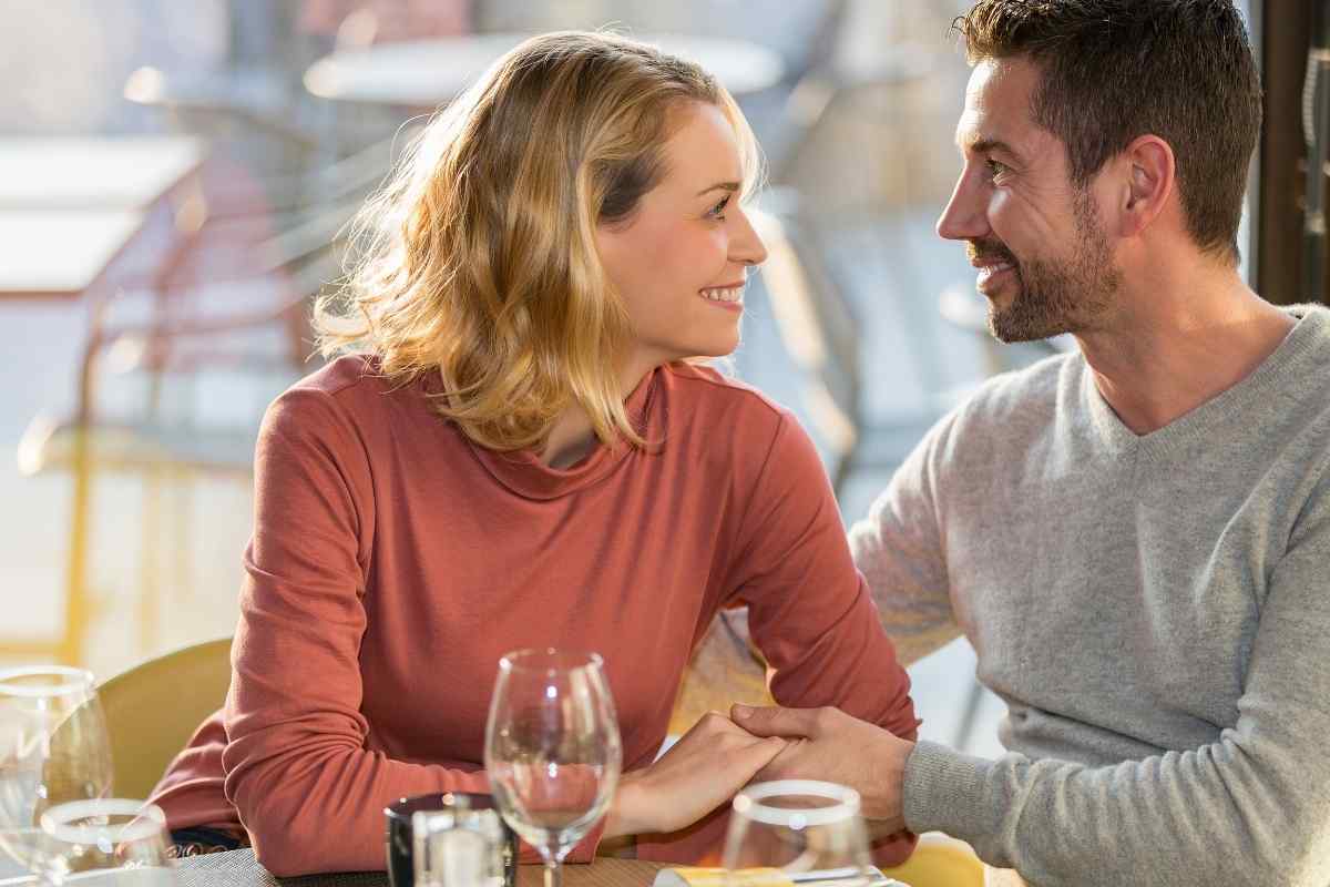 A joyful, luminous woman laughing openly in a social setting, reflecting the Leo woman's warmth and willingness to flirt directly