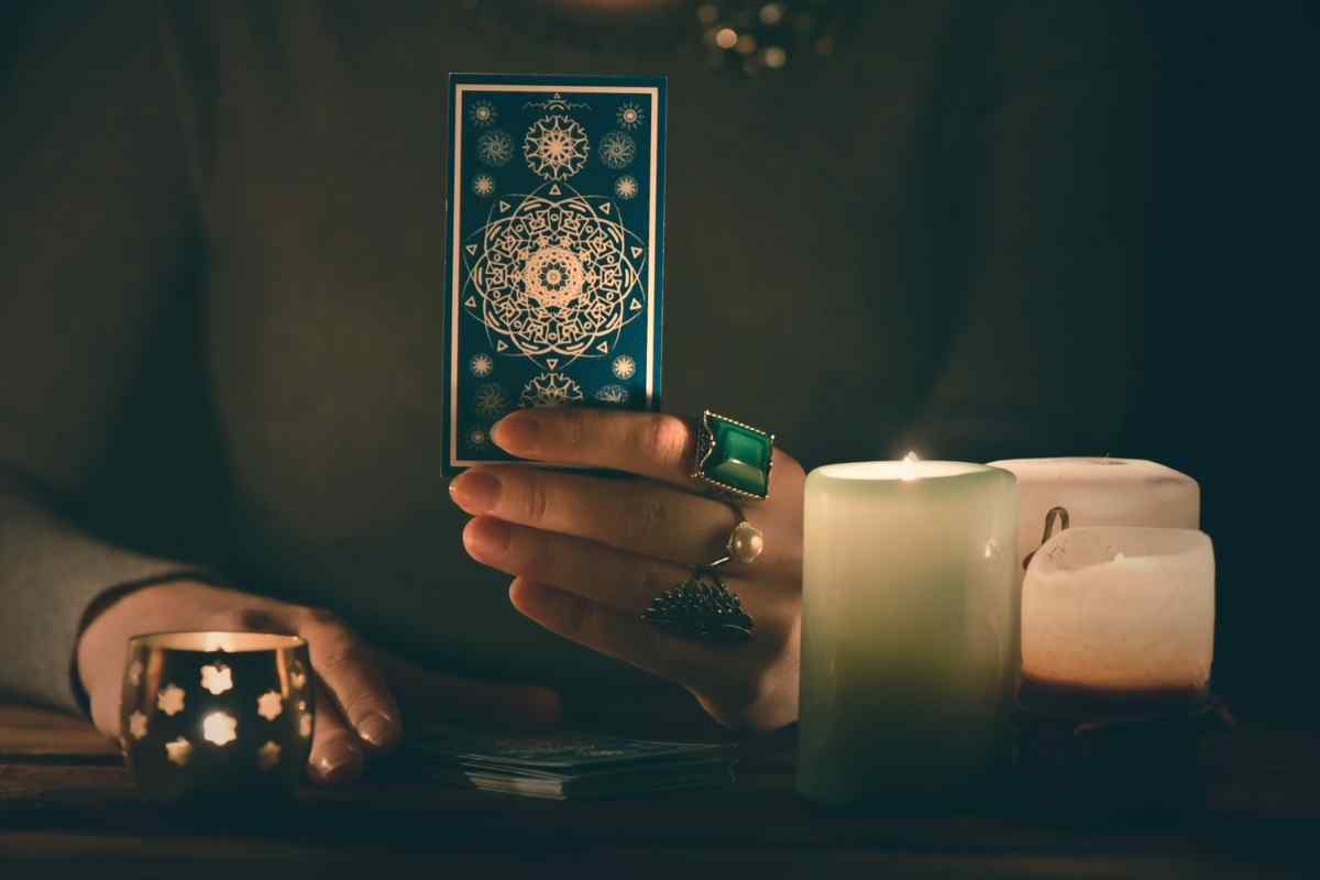 Seven of Swords tarot card held by candlelight during a reading