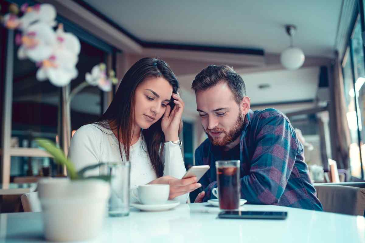 Couple sitting apart on opposite ends of a couch in a quiet, tense moment at home