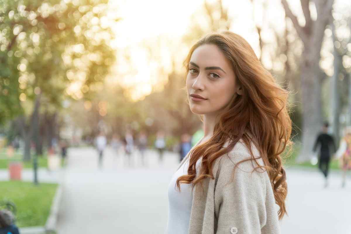 A woman sitting by a window with a thoughtful expression, soft afternoon light