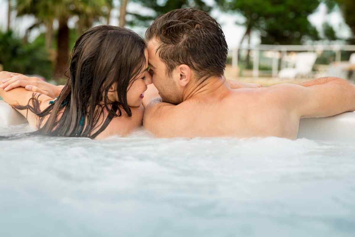 A couple sharing a close, warm moment, one partner's hands gently engaged with the other's hair