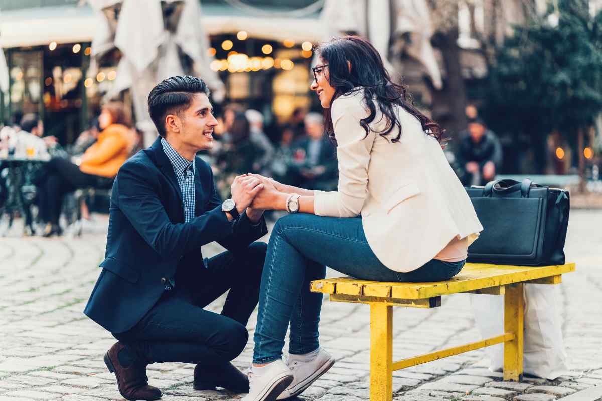 A couple in an animated, engaged conversation at a coffee shop, clearly enjoying each other's company