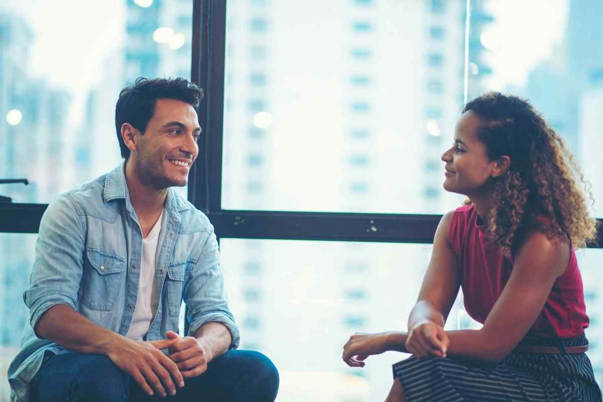 Two people with space between them on a couch, one looking away in silence while the other waits