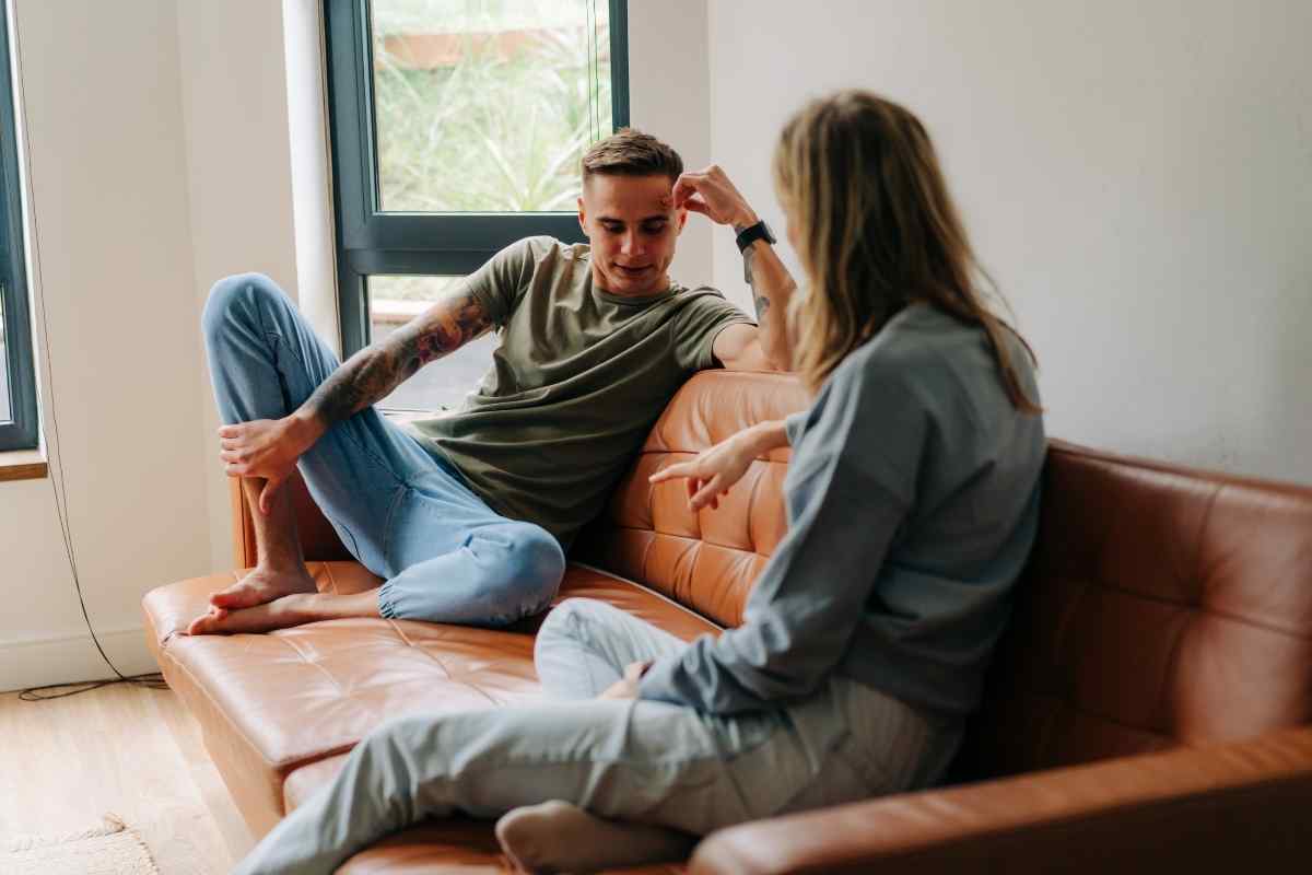 A couple in a tense exchange, the man's posture closed and his focus directed away from his partner