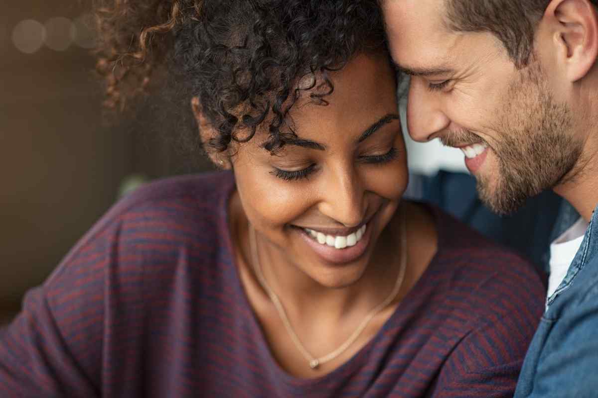 A woman and man sharing a warm, unhurried moment in a candlelit setting