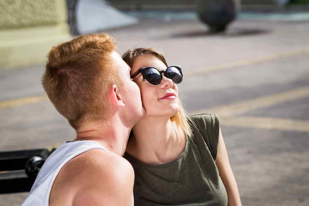 A couple in a warm, close moment, her partner attentive to her neck and shoulders